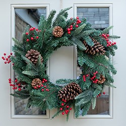 christmas wreath with berries and pinecones on front door